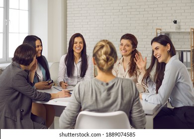 Team of happy young business women sitting around office table, discussing ideas, sharing funny stories and laughing. Group of smiling company employees talking and having fun in corporate meeting - Shutterstock ID 1889074585