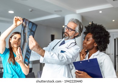 Team of healthcare professionals looking x-ray of the patient's lungs. Male and female doctor looking at lungs x-ray in hospital during covid19 pandemic
