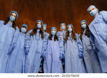 A team of healthcare professionals wearing protective gear, including masks and gloves, gathered in a clinical setting, focused and prepared for their tasks.