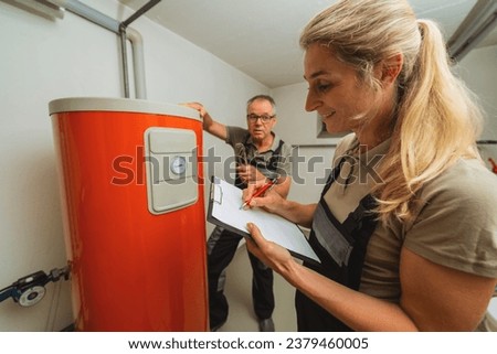 Team of heating engineers checks a old gas heating system, holding a Clipboard with checklist at a boiler room in a house. Gas heater replacement obligation concept image