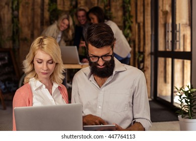 Team of hipsters using multimedia tools in the office