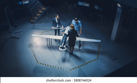 Team Of Industrial Aerospace Engineers Work On Unmanned Aerial Vehicle Concept. Designers Work On Pilotless Drone. Industrial Facility With Aircraft Capable Of Surveillance And Military. Elevated Shot