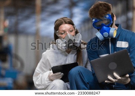 Team inspector chemical and hazmat wearing protective mask using laptop and write note on clipboard. Wastewater chemical residue in factory. Analysing harmful substances to human body environment.