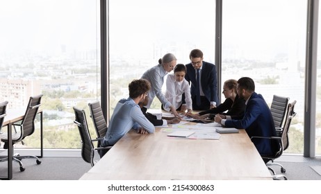Team of interns and teacher studying marketing, working on startup project together. Business coworkers brainstorming, negotiating on sales reports at table in meeting room. Teamwork concept