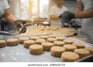 Team of kitchen workers forms cutlets on large wooden table