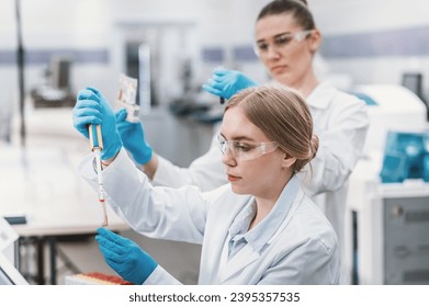 team of laboratory technicians conduct series of tests on  chemical analyzer in laboratory. Two female scientists work in modern equipped computer laboratory doing tests with tubes and pipette - Powered by Shutterstock