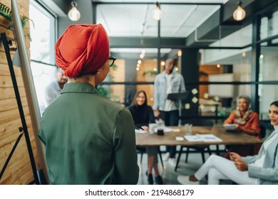 Team Leader Giving A Speech During A Boardroom Meeting. Muslim Businesswoman Sharing Her Creative Strategy With Her Colleagues. Businesswoman Wearing A Headscarf In A Multicultural Workplace.