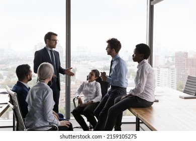 Team leader lead corporate meeting with multi ethnic teammates in modern office boardroom. Group of employees, staff members take part in morning briefing with company boss. Business meeting concept