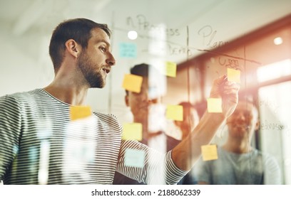 Team leader planning and writing on sticky notes while brainstorming, talking or sharing vision or ideas. Diverse group of creative business people meeting together for market training in new