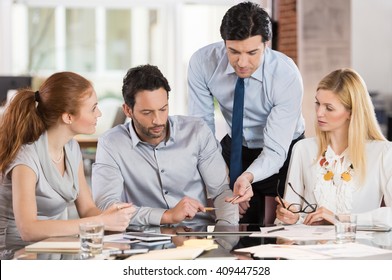 Team Leader Pointing Charts And Graphs On Digital Tablet. Businesspeople Working As A Team In The Office. Businesspeople Working Together And Discussing About New Ideas For Marketing.