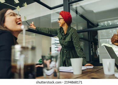 Team Leader Sharing Creative Ideas During A Meeting. Cheerful Muslim Businesswoman Using Sticky Notes While Brainstorming With Her Team. Businesswoman Wearing A Headscarf In A Multicultural Workplace.