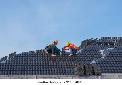 A Team Male Roofers Use A Cordless Electric Battery Drill To Fire Screws To Install Concrete Roofing Slabs Or C-packs On Home Structure Construction