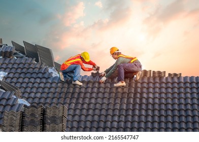 A Team Male Roofers Uses A Cordless Electric Battery Drill To Fire Screws To Install Concrete Roofing Slabs Or C-packs On Home Structure Construction