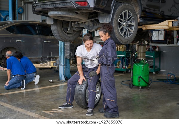 Team of mechanic and\
technicians work in car service garage to maintainance customer\
car