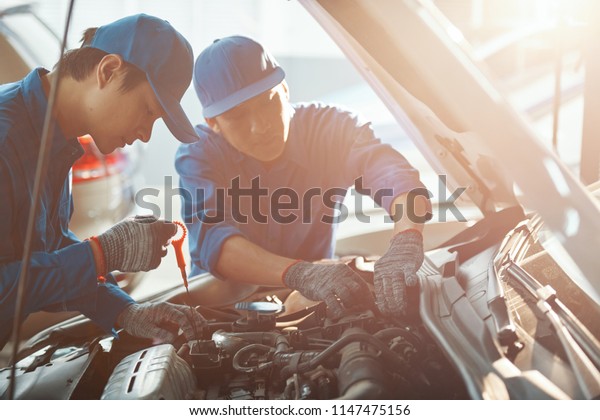 Team of\
mechanics repairing car in sunny\
garage