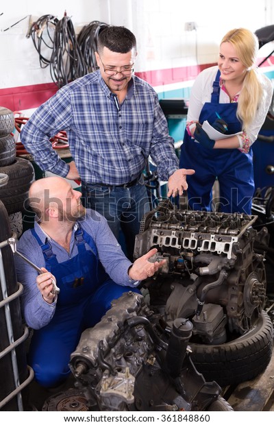 Team of\
mechanics repairing engines in a\
workshop