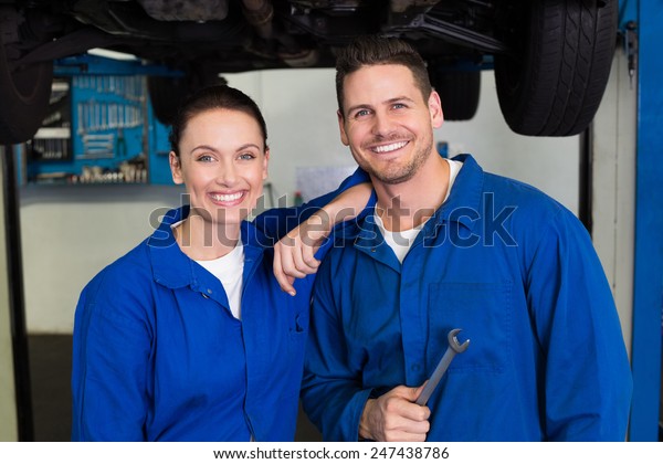 Team\
of mechanics smiling at camera at the repair\
garage