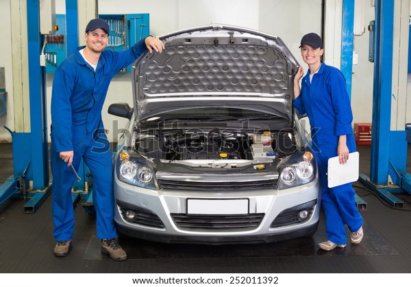 Team\
of mechanics smiling at camera at the repair\
garage