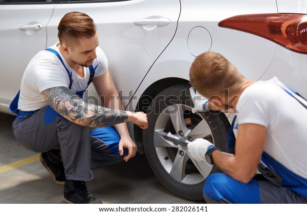 Team of\
Mechanics Working On a Car at the\
Garage