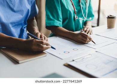 Team, medical analysts and doctors consulting with paperwork of graphs, data and charts in hospital conference room. Healthcare staff discussing statistics, results of research and innovation. - Powered by Shutterstock