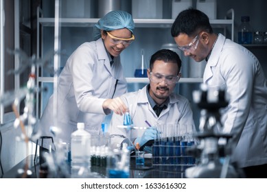 Team Of Medical Research Scientists Collectively Working On A New Generation Experimental Drug Treatment. Laboratory Looks Busy, Bright And Modern.