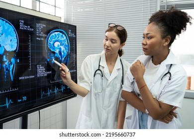 Team Of Medical Scientists Meeting In The Brain Research Laboratory By Monitor Showing MRI, CT Scans Brain Images. Group Of Female Scientist Discussing Magnetic Resonance Image (MRI) Of The Brain