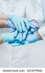 Team of medical workers in blue gloves holding hands together. Closeup. Unity concept.