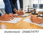 A team meeting of business people and a lawyer in formal suits is taking place at a desk, discussing a contract and various aspects of the law and litigation.