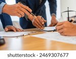 A team meeting of business people and a lawyer in formal suits is taking place at a desk, discussing a contract and various aspects of the law and litigation.