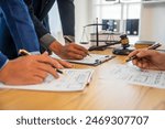 A team meeting of business people and a lawyer in formal suits is taking place at a desk, discussing a contract and various aspects of the law and litigation.