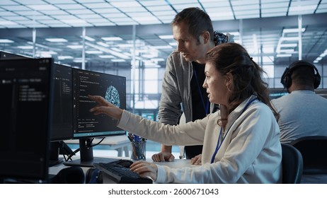IT team members programming scripts on computer, employing AI machine learning. Software developer and coworker manipulating lines of code for artificial intelligence applications, camera B