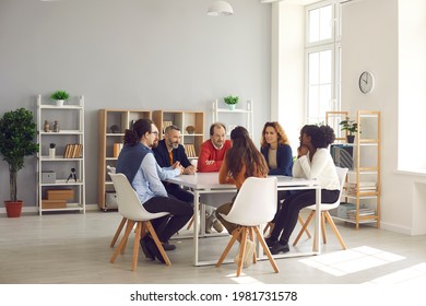 Team of mixed race business people sitting around big table in modern office space. Group of diverse company employees discussing projects and taking decisions together in corporate meeting - Powered by Shutterstock