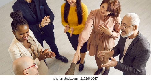 Team Of Multiracial Business People At Meeting. Happy Woman Who's Done Good Job Getting Coworkers' Respect, Gratitude, Greetings And Applause And Exchanging Handshake With Grateful Leader. High Angle