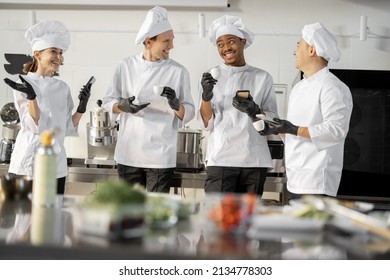 Team of multiracial cooks having conversation during a coffee break in the kitchen. Well-dressed chefs resting and having fun in the restaurant kitchen. Teamwork and leisure time on work - Powered by Shutterstock