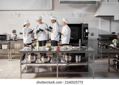 Team of multiracial cooks having conversation during a coffee break in the kitchen. Well-dressed chefs resting and having fun in the restaurant kitchen. Teamwork and leisure time on work - Powered by Shutterstock