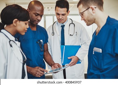 Team of multiracial doctors at hospital discussing a patient, Doctors using tablet - Powered by Shutterstock