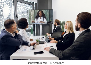 Team of multiracial five business people, healthcare experts, having video conference meeting with young, pretty African doctor scientist, talking about the medical case or clinical trial
