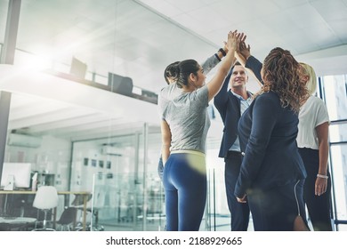Team number one. Successful group of business people giving a high five in support team building achievement. Work colleagues celebrating good teamwork project together in modern conference office. - Shutterstock ID 2188929665