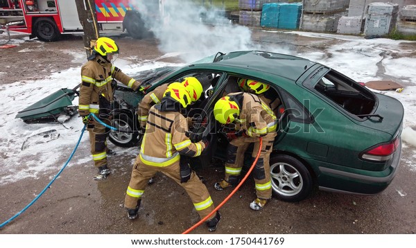 Team off Firefighters trying\
to cut open car door to save person involved in the accident.\
