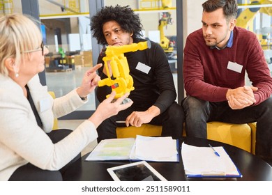 Team in office discussing robotics development and process automation using a gripper arm model. Ideal for engineering, programming, and industry concepts. - Powered by Shutterstock