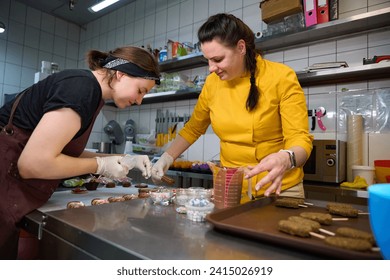 Team of pastry chefs decorating together cakesicles on kitchen countertop - Powered by Shutterstock