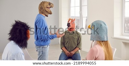 Team of people with animal faces having an interesting discussion during their meeting in the office. Group of men and women wearing funny crazy bizarre animal masks sitting in a circle and talking