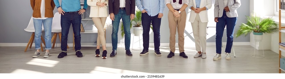 Team of people in smart casual clothes at work in office. Group of men and women in shirts and jackets, jeans and trousers standing together. Cropped, low section shot of human legs. Header background - Shutterstock ID 2159481639