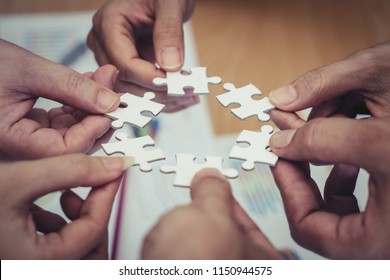 Team placing four puzzles jigsaw together for team concept - Shutterstock ID 1150944575