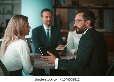 Team players discuss work in the office. Selective focus on businessman discussing with female colleague in the foreground. High quality photo - Powered by Shutterstock