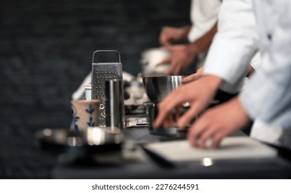 Team of professional chefs preparing food in a commercial kitchen. Cooks in the production process of system catering. An inside view of a pro catering kitchen in Spain. Extreme narrow depth of field. - Powered by Shutterstock