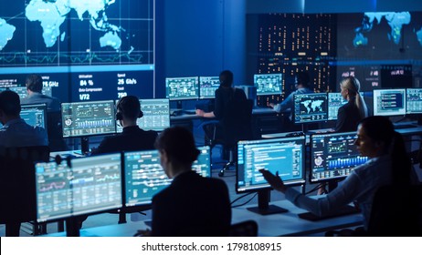 Team of Professional Computer Data Science Engineers Work on Desktops with Screens Showing Charts, Graphs, Infographics, Technical Neural Network Data and Statistics. Dark Control and Monitoring Room.