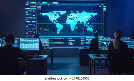 Team of Professional Computer Data Science Engineers Work on Desktops with Screens Showing Charts, Graphs, Infographics, Technical Neural Network Data and Statistics. Dark Control and Monitoring Room.