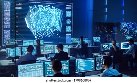 Team Of Professional Computer Data Science Engineers Work On Desktops With Screens Showing Charts, Graphs, Infographics, Technical Neural Network Data And Statistics. Dark Control And Monitoring Room.