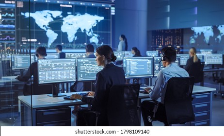 Team of Professional Computer Data Science Engineers Work on Desktops with Screens Showing Charts, Graphs, Infographics, Technical Neural Data and Statistics. Low Key Control and Monitoring Room.